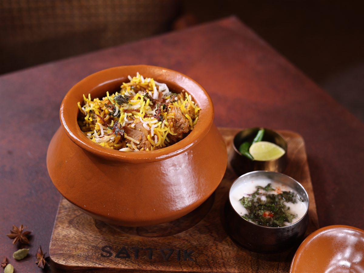 Kathal biryani served in a clay handi, with raita and lemon on the side